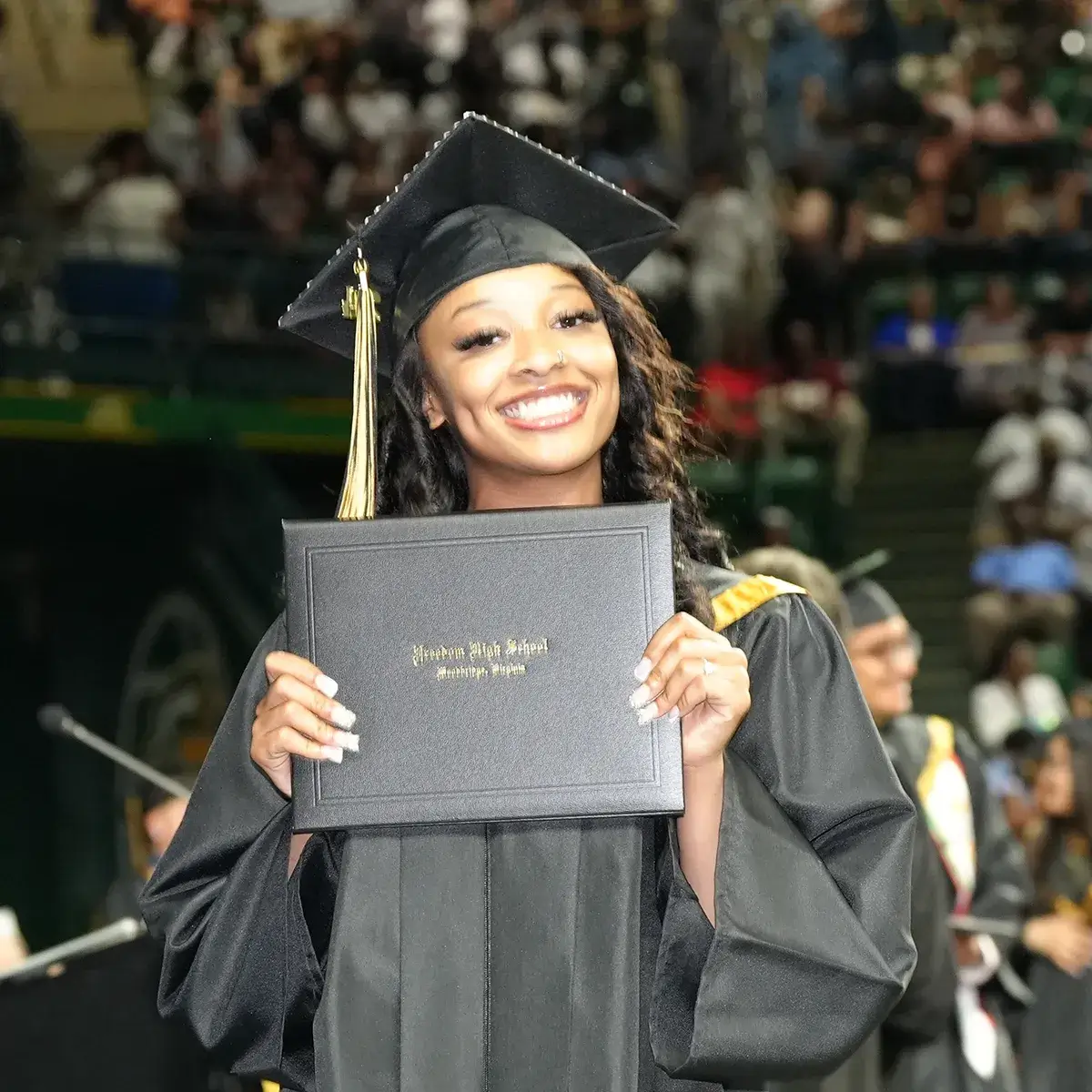 Freedom High School graduate holding up her diploma at the 2024 graduation ceremony