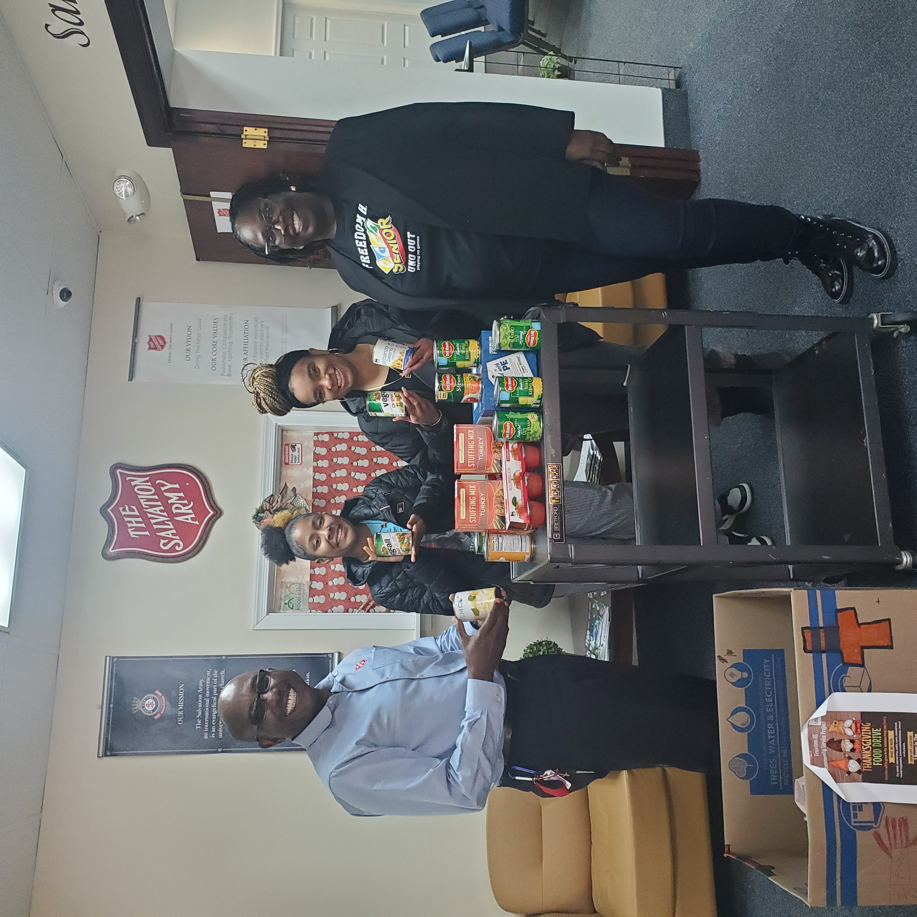 students with their sponser and a representative from Salvation Army posing with donations