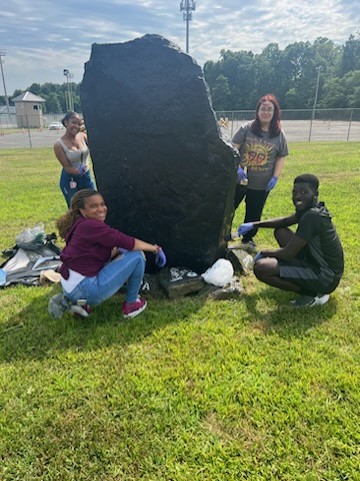 seniors posing next to the large class of 2024 rock, which is painted black